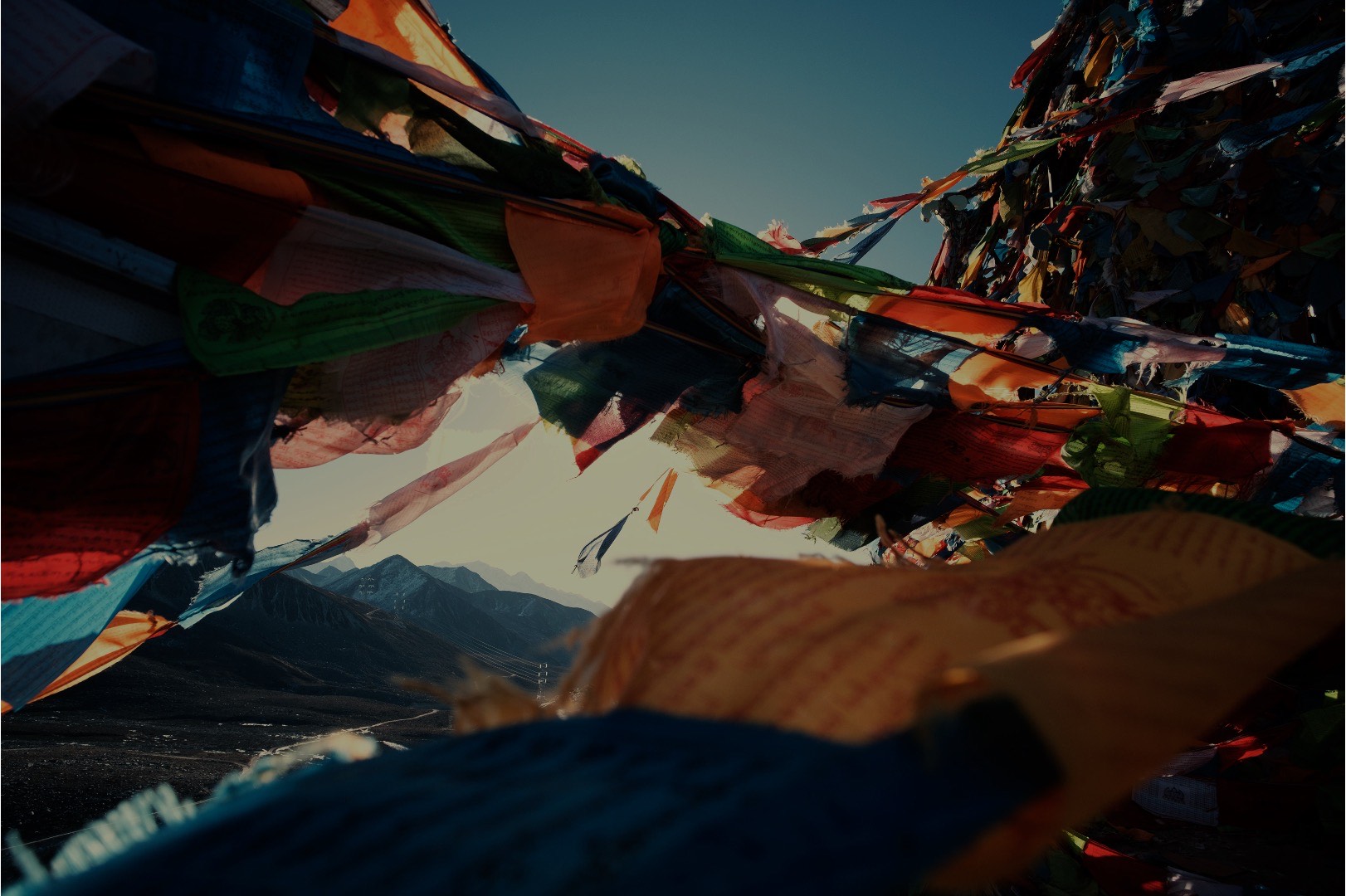 Prayer flags strung above a mountain valley at dusk